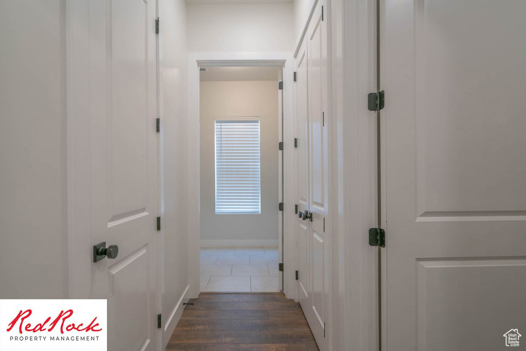 Corridor with dark wood-style flooring and baseboards