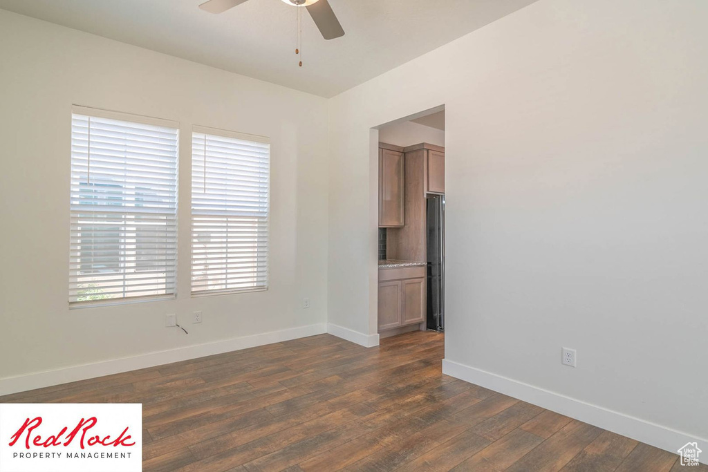 Spare room with a ceiling fan, baseboards, and dark wood-style flooring