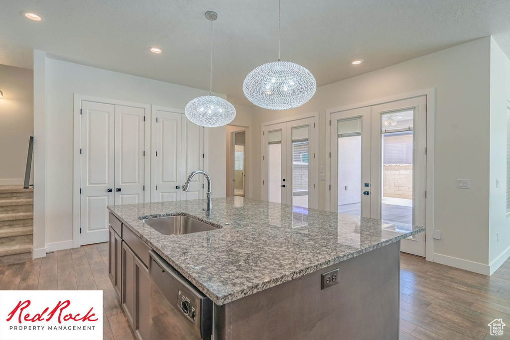 Kitchen featuring a sink, dishwasher, light wood-type flooring, baseboards, and recessed lighting