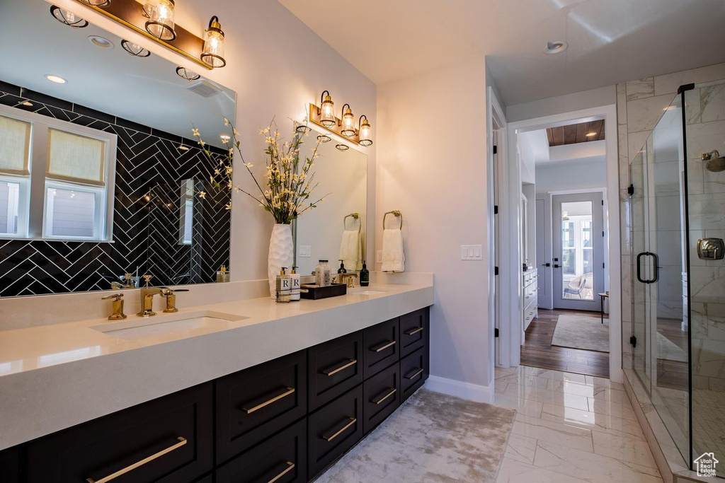 Full bath with marble look tile flooring, double vanity, and a shower stall
