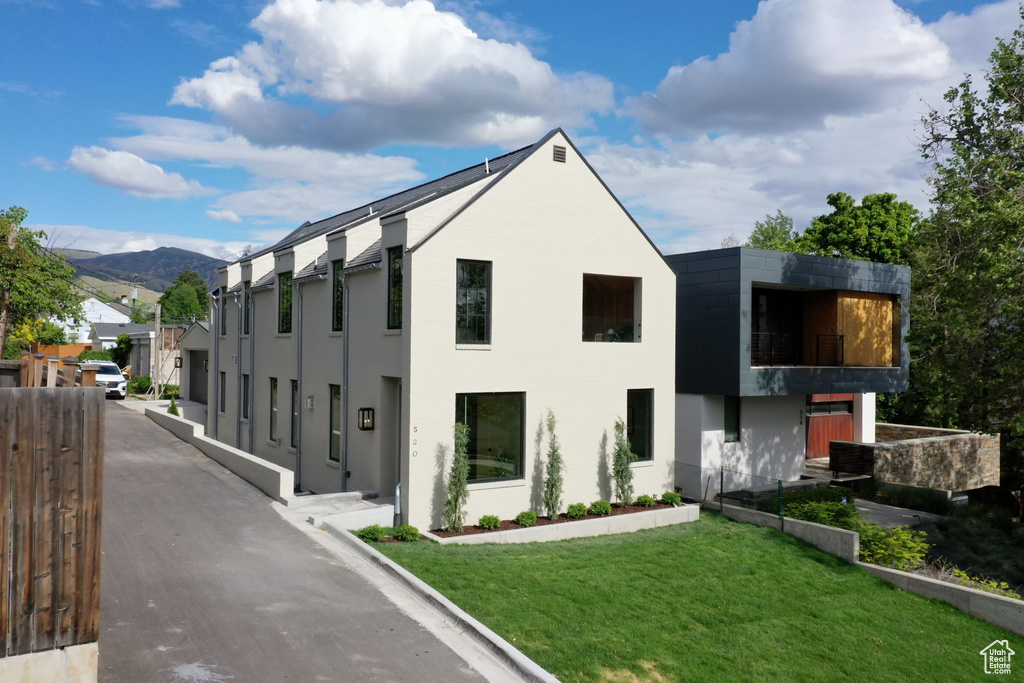 View of front of house featuring a balcony, a front yard, a mountain view, and stucco siding