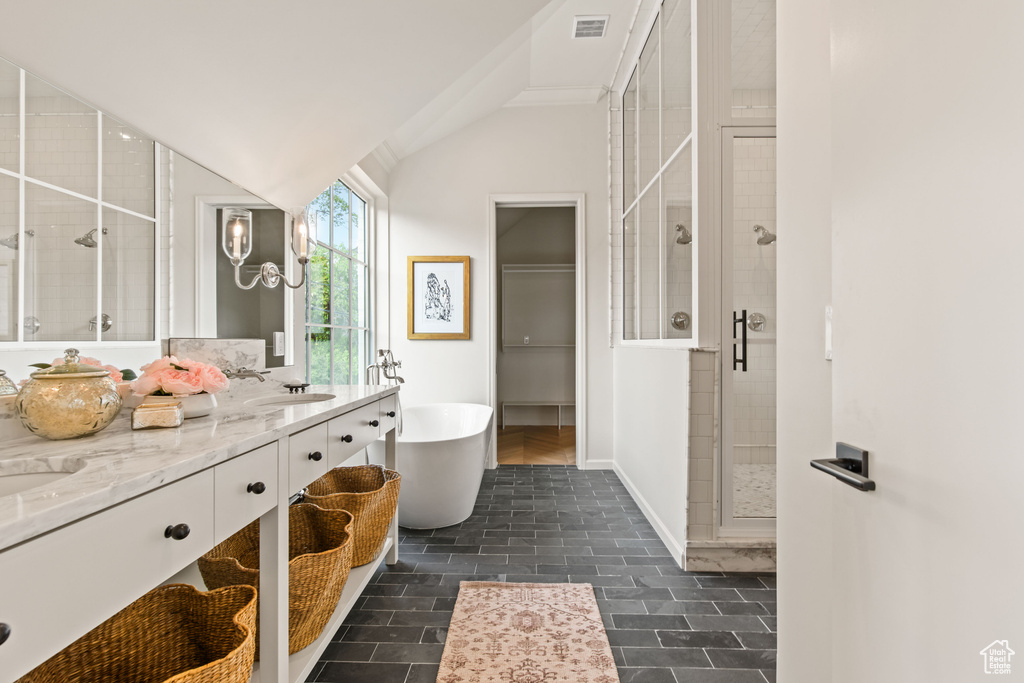 Full bath featuring a shower stall, a soaking tub, double vanity, vaulted ceiling, and baseboards