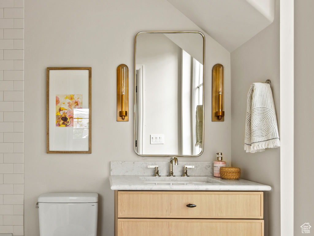 Bathroom with toilet, vaulted ceiling, baseboards, vanity, and a bathtub