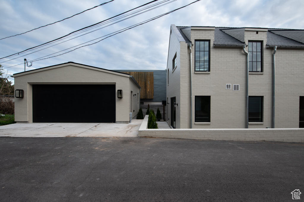 View of front of home with an outdoor structure, brick siding, and a garage