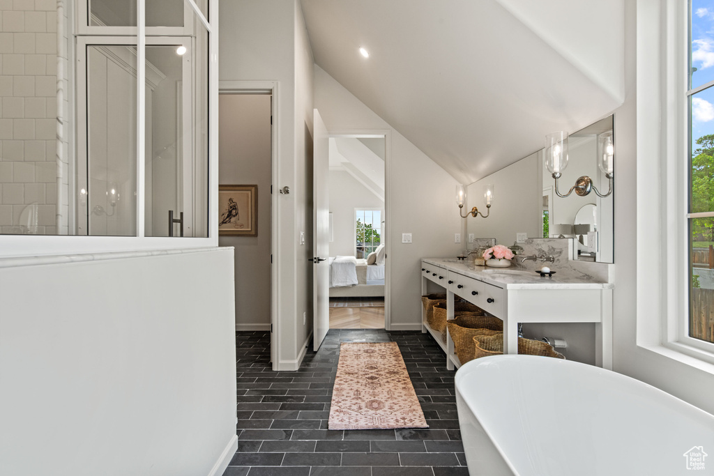 Bathroom with ensuite bath, a freestanding bath, lofted ceiling, tile patterned floors, and vanity