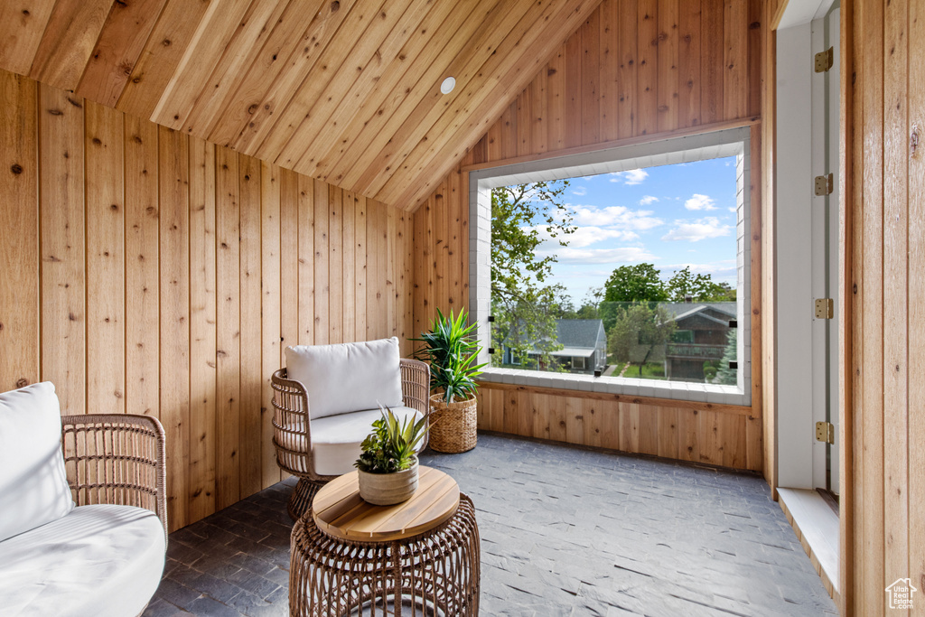 Sitting room with wood walls, lofted ceiling, brick flooring, and wood ceiling