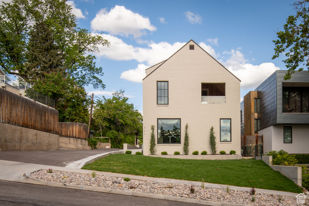 Contemporary home with a front yard and brick siding