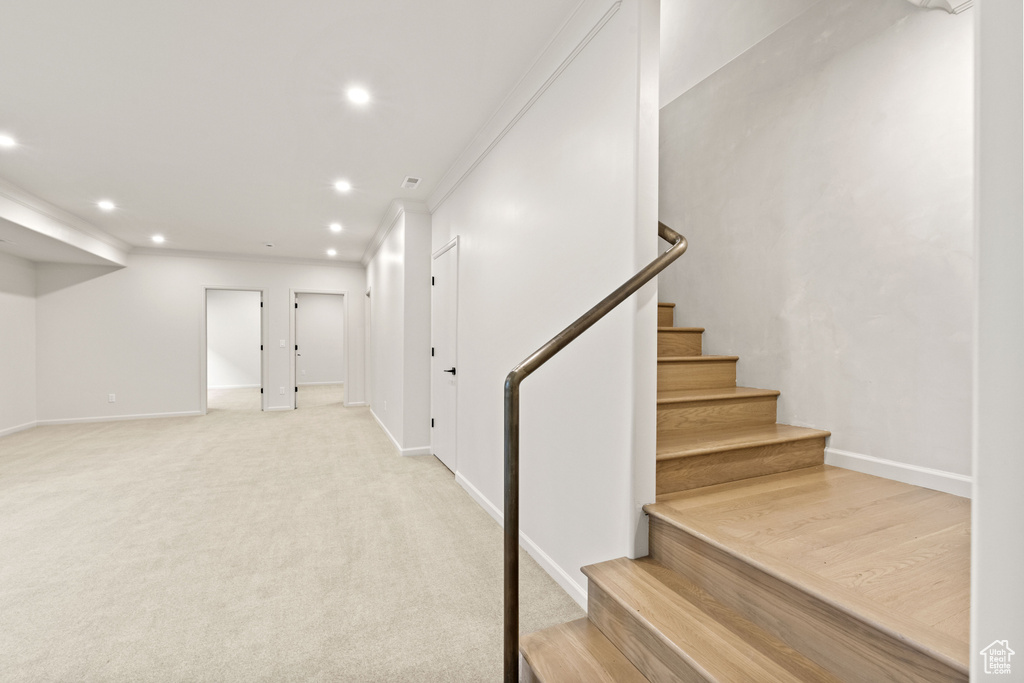 Below grade area with recessed lighting, baseboards, stairway, light carpet, and ornamental molding