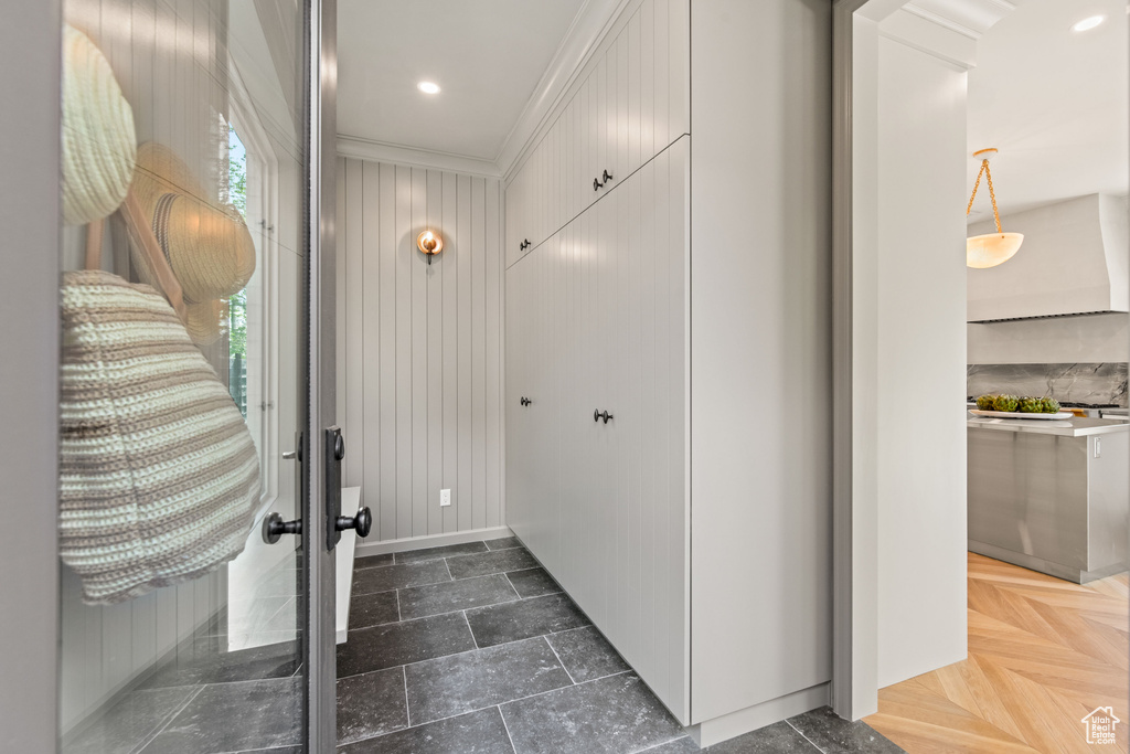 Entrance foyer featuring ornamental molding, baseboards, and wood walls