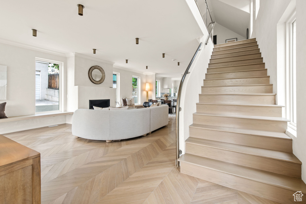 Living room with stairway, a fireplace, and crown molding
