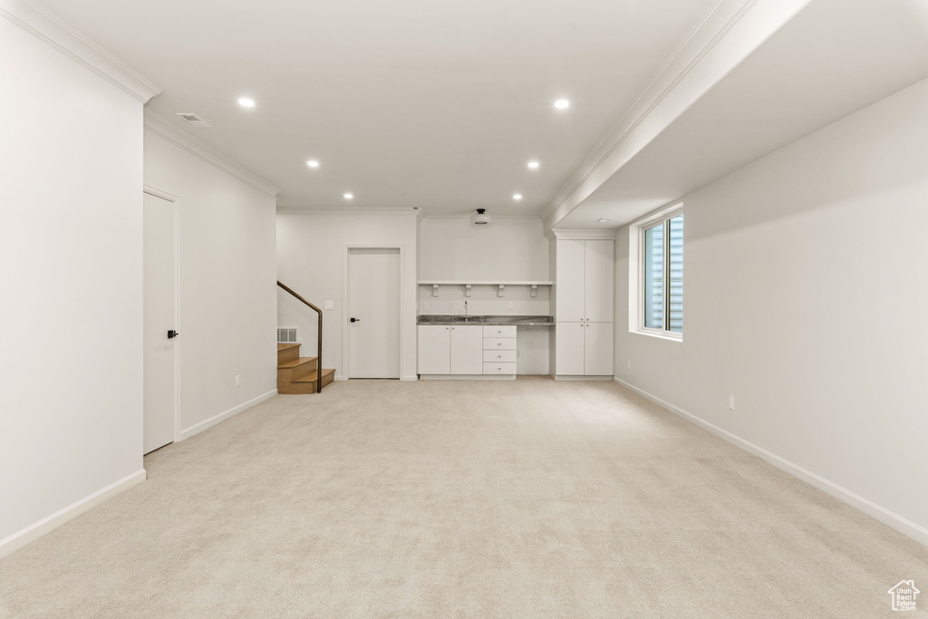 Unfurnished living room featuring ornamental molding, stairway, recessed lighting, light carpet, and baseboards
