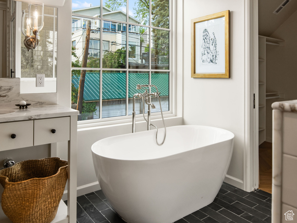 Bathroom featuring vaulted ceiling, a soaking tub, tile patterned floors, and vanity