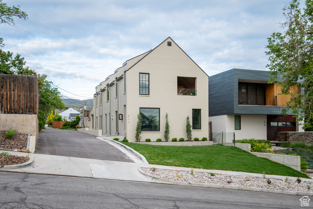 View of front of house with a front lawn, driveway, and a balcony