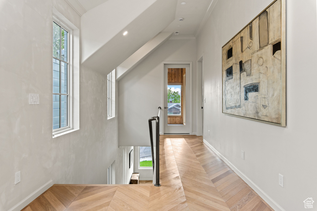 Corridor with an upstairs landing, baseboards, and crown molding