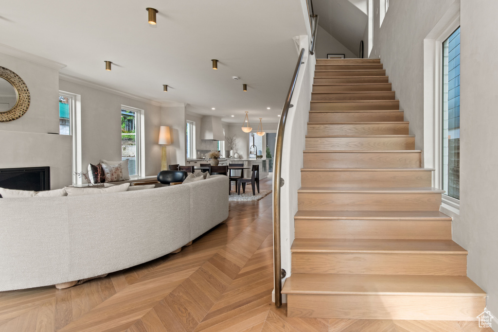 Stairway with a fireplace, ornamental molding, and recessed lighting