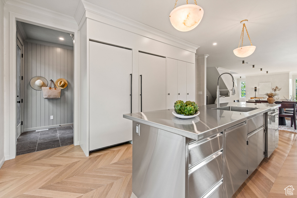 Kitchen with stainless steel counters, a sink, hanging light fixtures, baseboards, and dishwasher