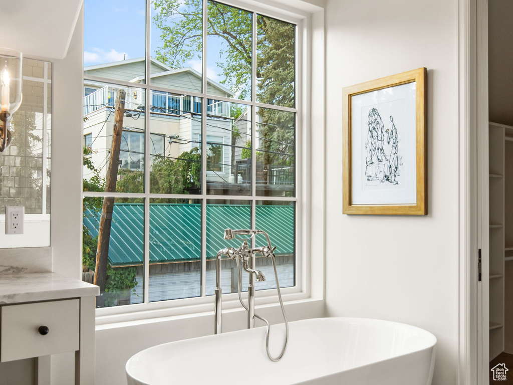 Bathroom featuring a soaking tub, tile patterned floors, vanity, lofted ceiling, and baseboards