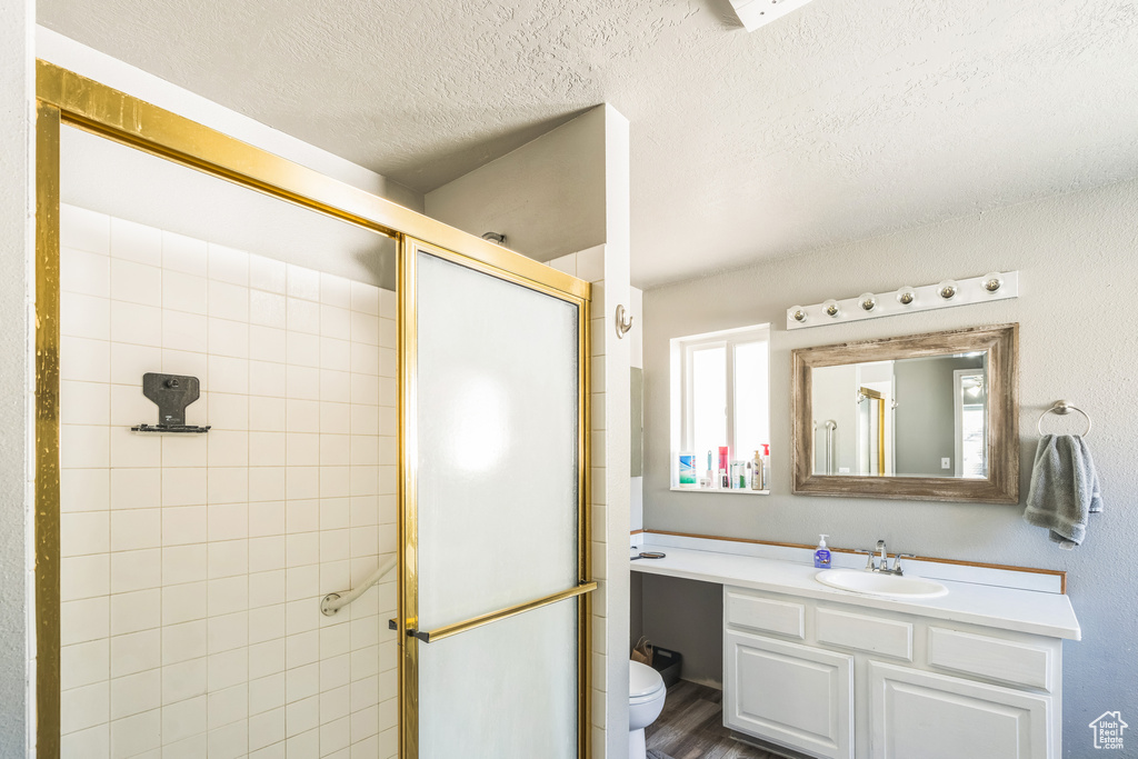 Bathroom featuring a stall shower, toilet, vanity, a textured ceiling, and wood finished floors