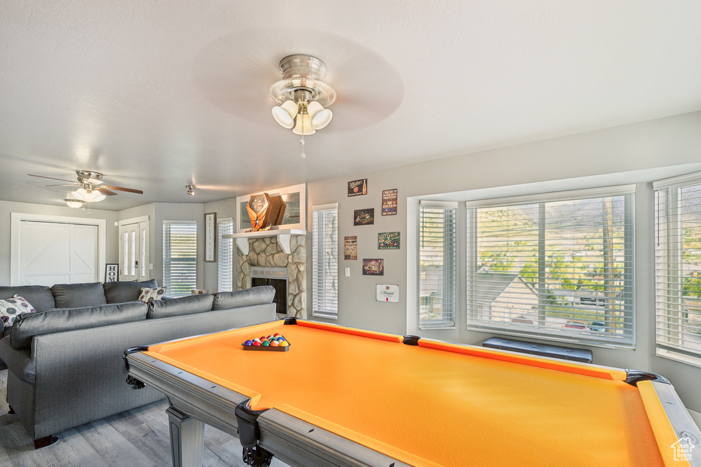 Rec room with a ceiling fan, wood finished floors, pool table, and a fireplace