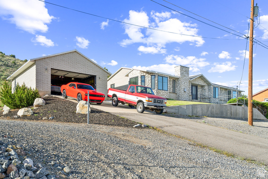 View of front of house featuring a garage, an outbuilding, and stone siding