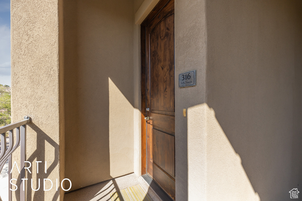 Property entrance with stucco siding and a balcony