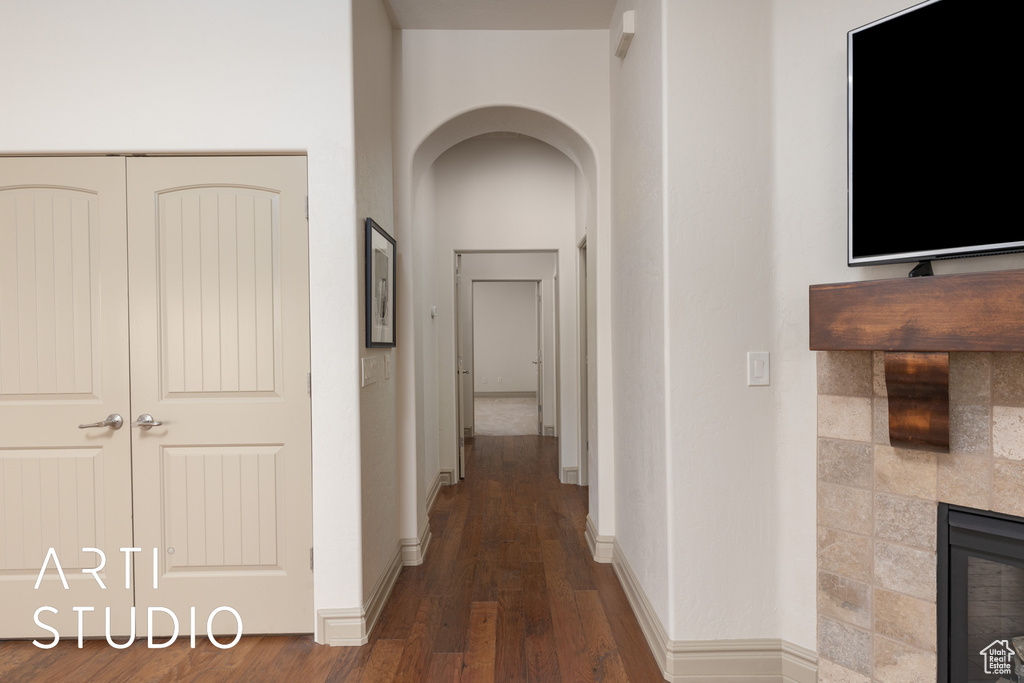 Corridor with arched walkways, wood finished floors, and baseboards
