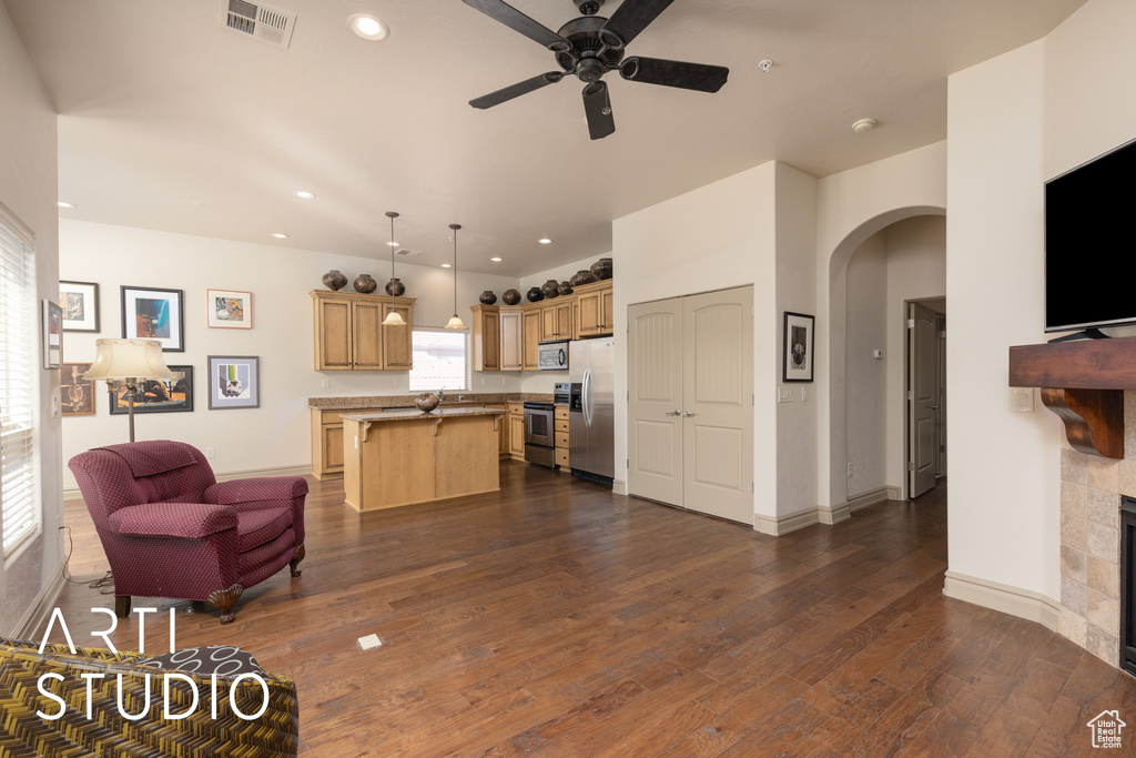 Living room featuring arched walkways, ceiling fan, dark wood-style flooring, a fireplace, and recessed lighting