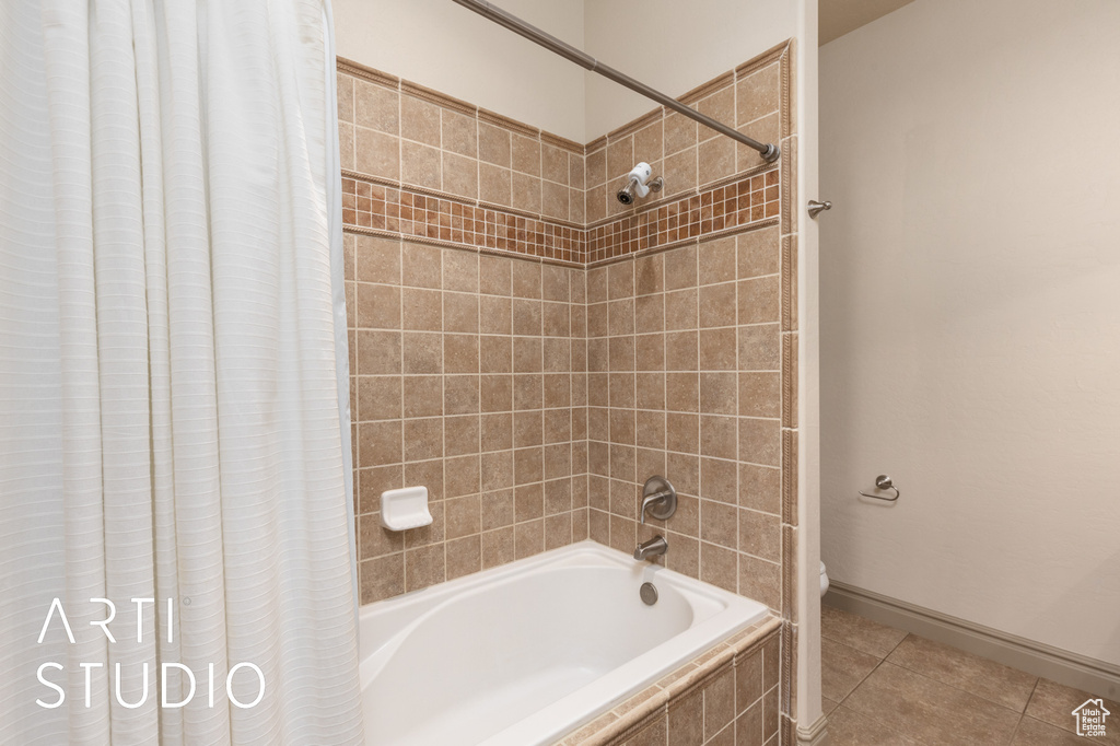 Full bath with shower / tub combo with curtain, tile patterned floors, toilet, and baseboards