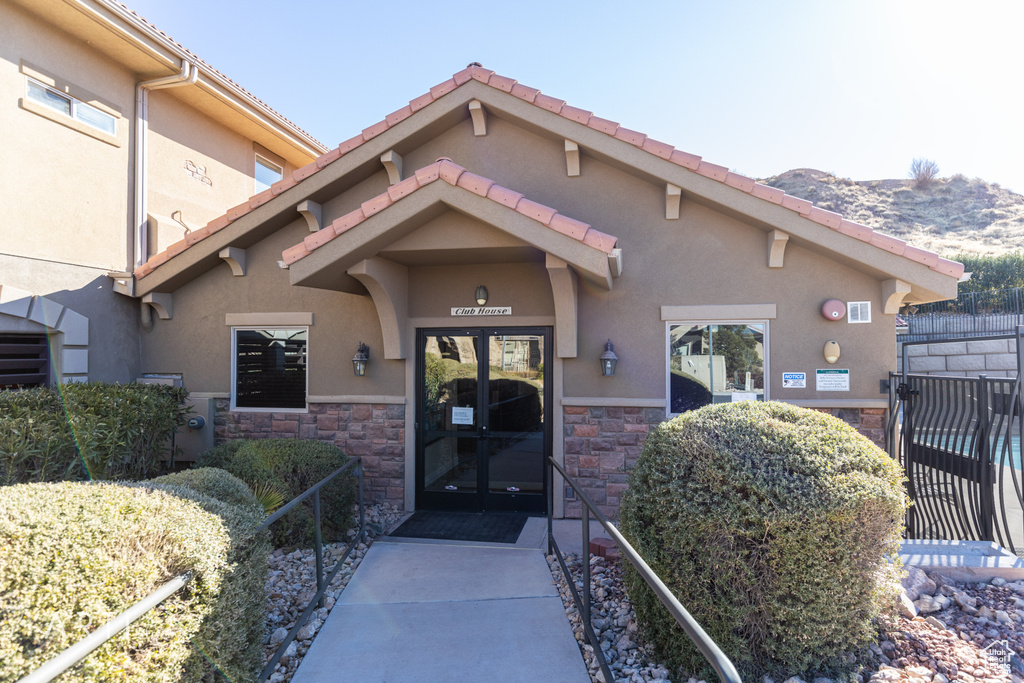 Property entrance with stone siding, stucco siding, a mountain view, french doors, and a tile roof