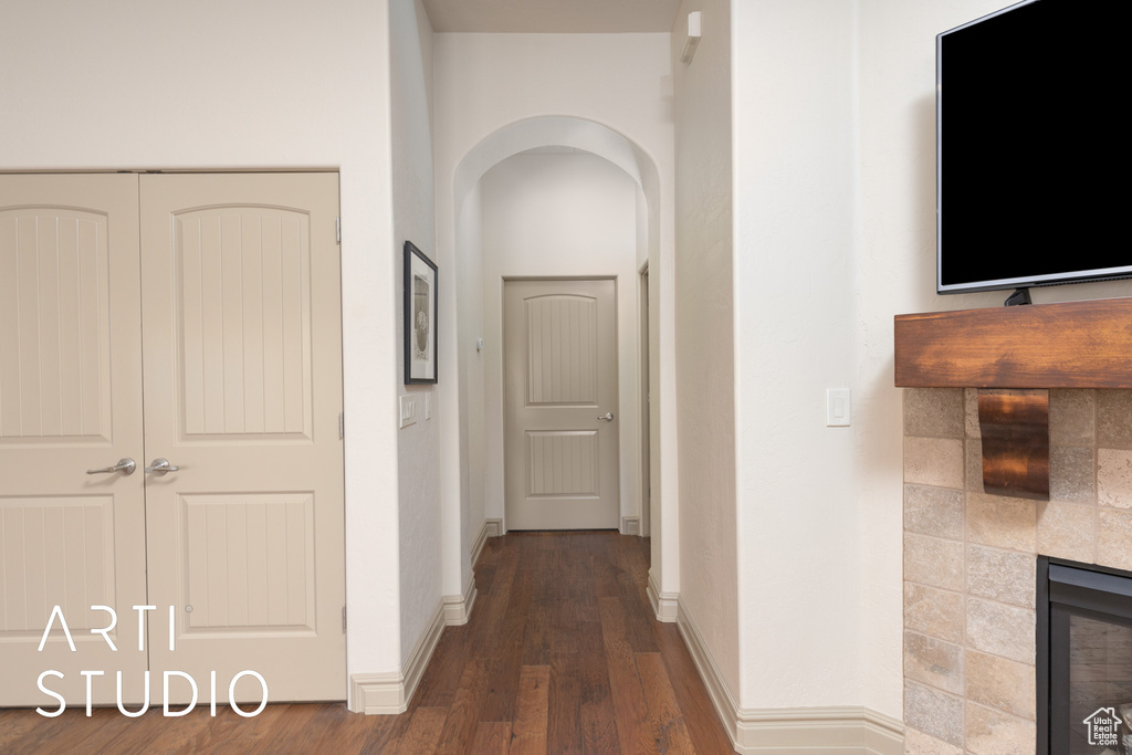 Hallway with arched walkways, wood finished floors, and baseboards