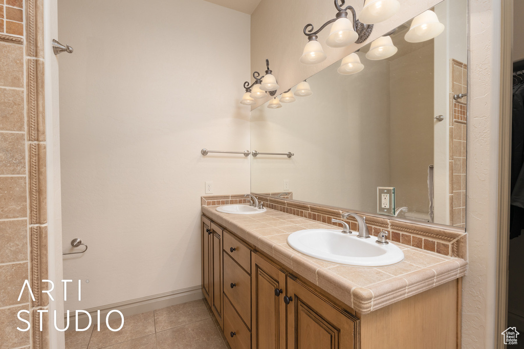 Full bathroom with tile patterned flooring, double vanity, baseboards, and a chandelier