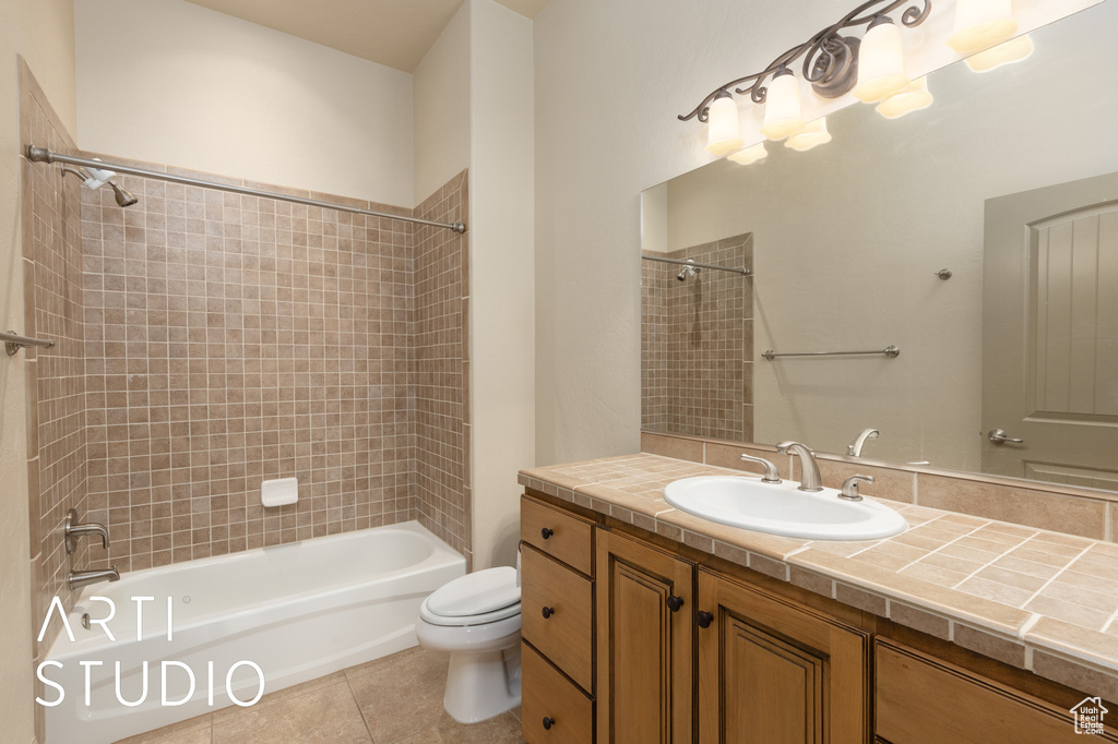Bathroom with toilet, tile patterned flooring,  shower combination, and vanity