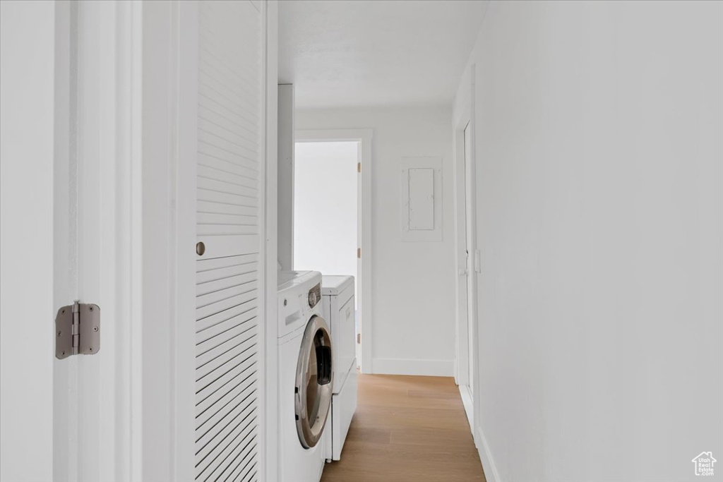 Washroom with washing machine and dryer, light wood-type flooring, and baseboards