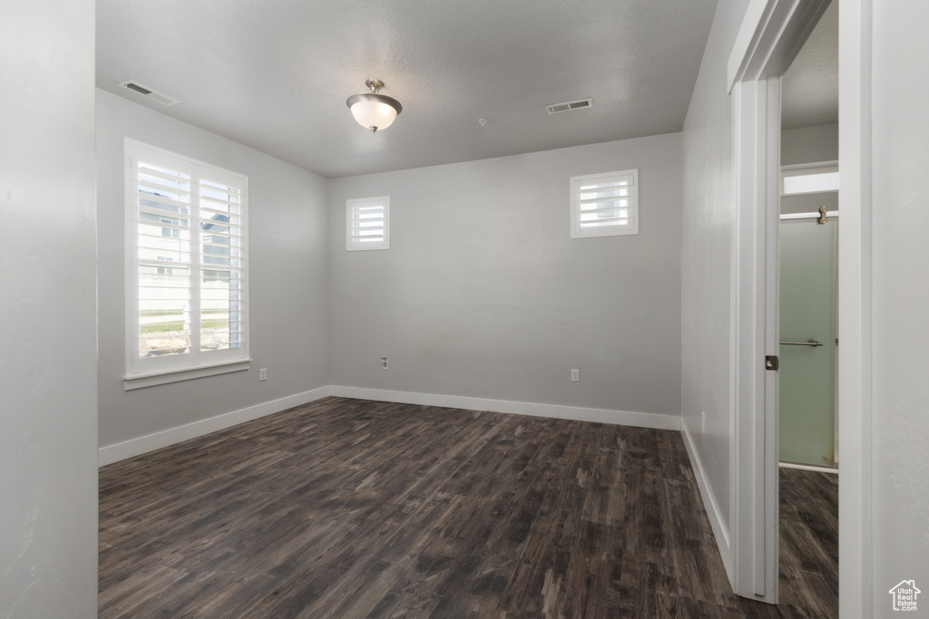 Spare room with healthy amount of natural light, dark wood-style flooring, and baseboards