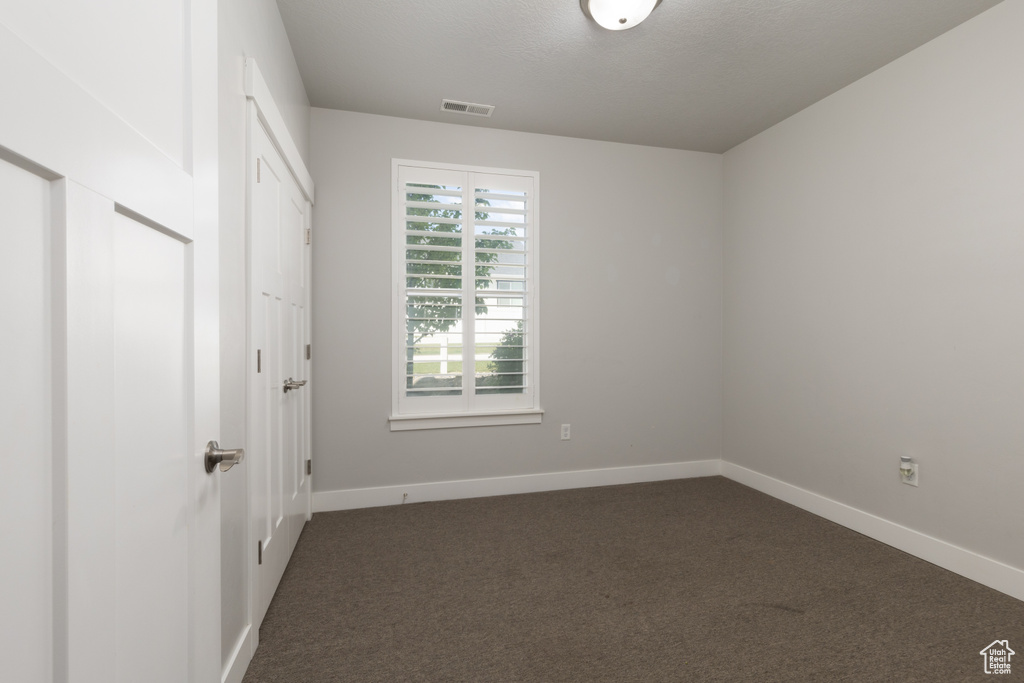 Unfurnished bedroom with dark colored carpet, baseboards, and a closet
