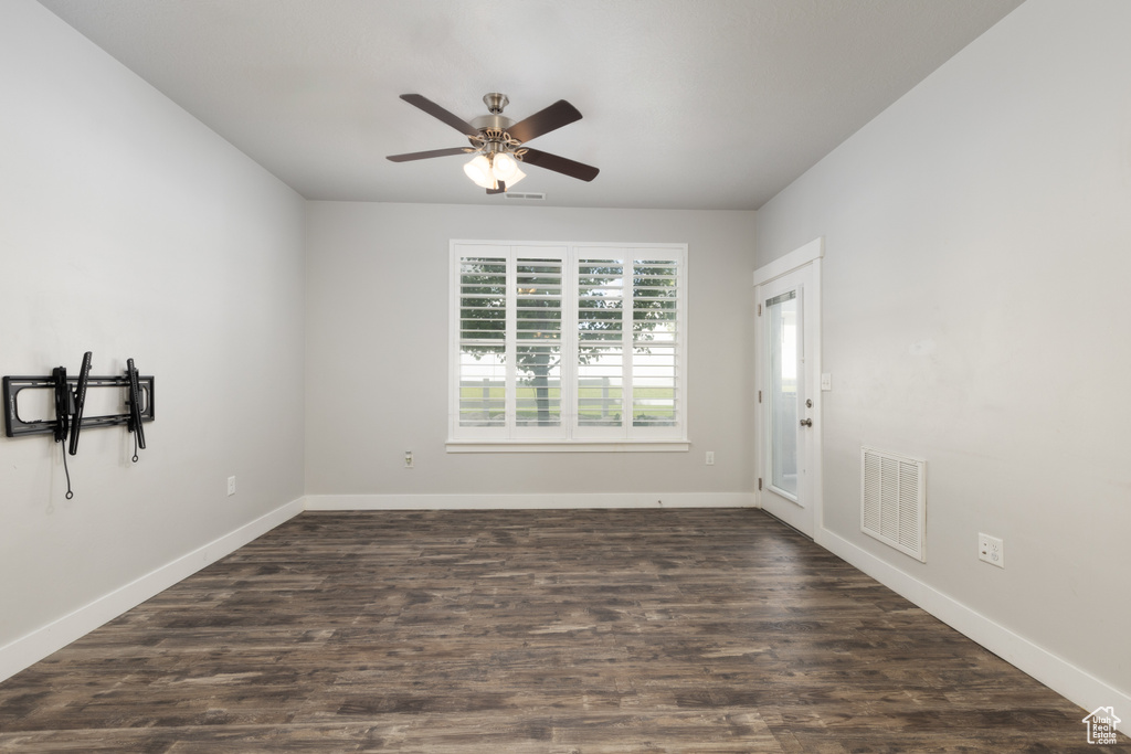 Spare room featuring baseboards, ceiling fan, and dark wood finished floors
