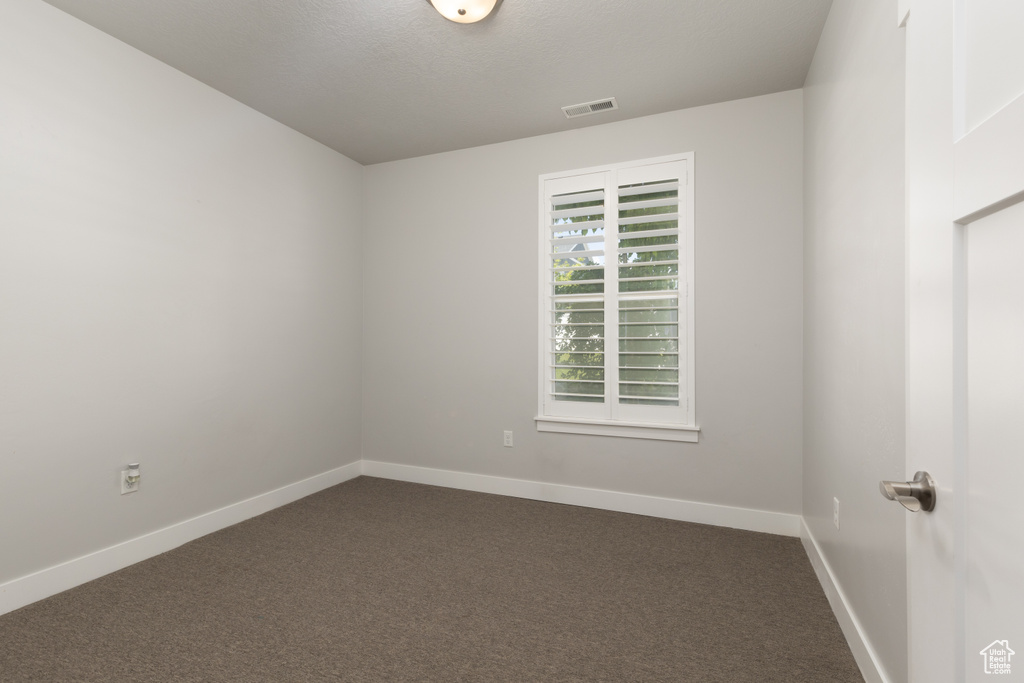 Unfurnished room with dark colored carpet and baseboards