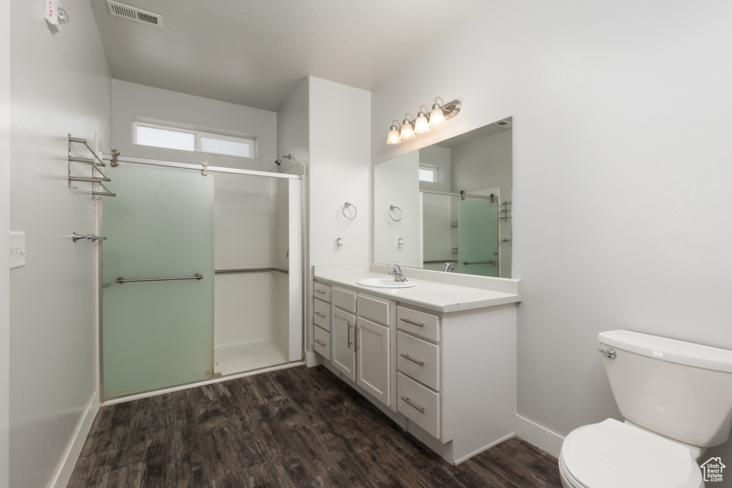 Full bathroom with a shower stall, toilet, wood finished floors, baseboards, and vanity