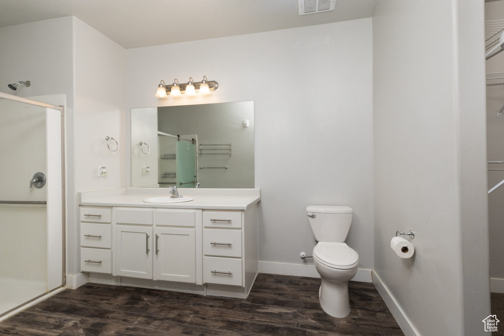 Full bath with a stall shower, wood finished floors, toilet, vanity, and baseboards