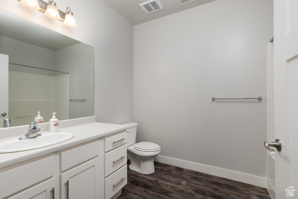 Full bath with vanity, toilet, wood finished floors, and baseboards