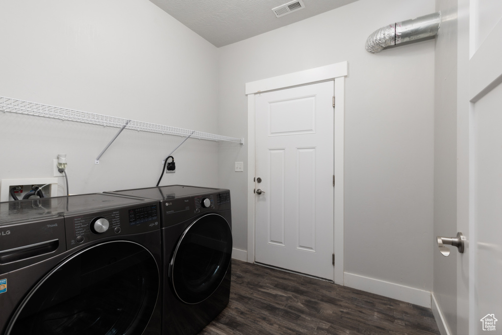 Laundry room featuring washing machine and dryer, dark wood-style flooring, and baseboards