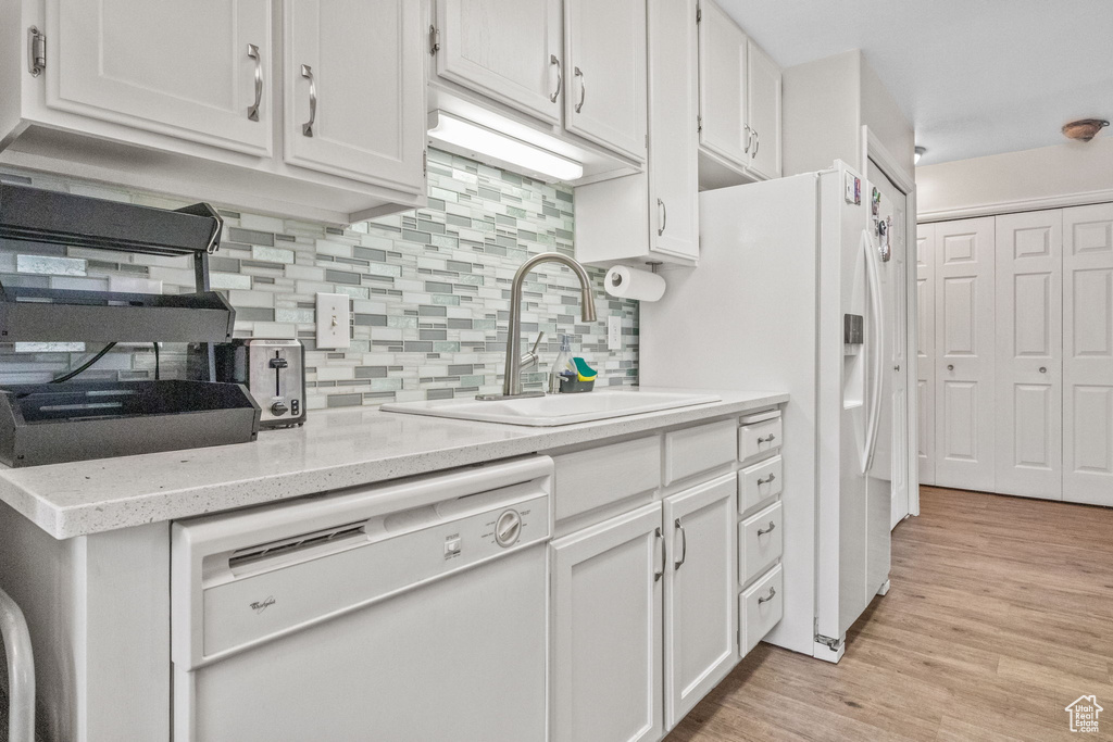 Kitchen featuring white appliances, a sink, and white cabinets