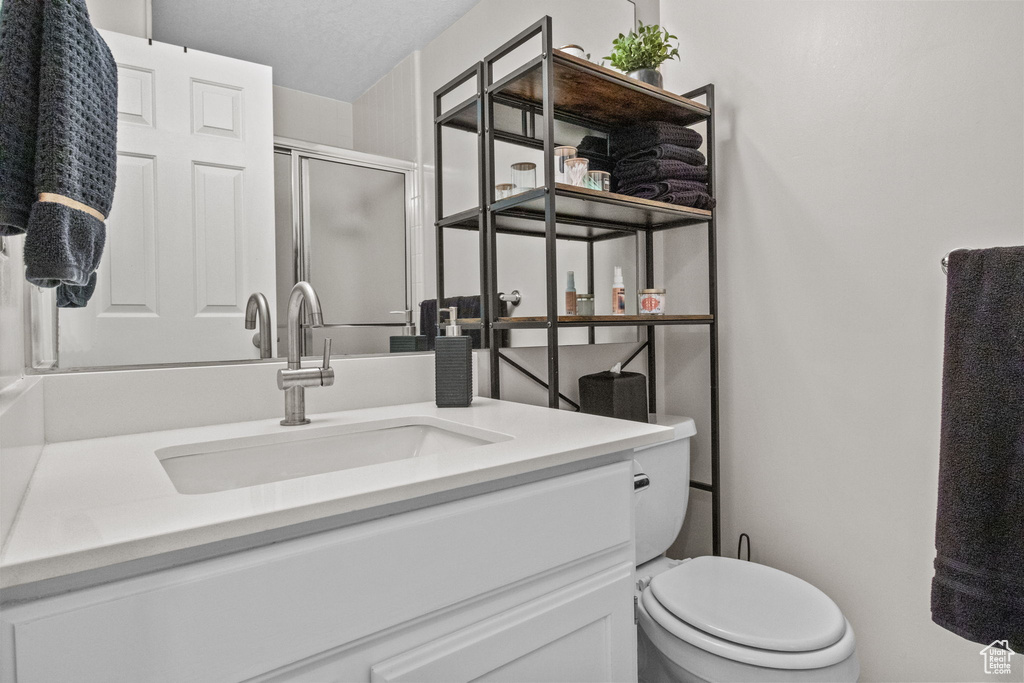 Bathroom with a stall shower, vanity, and toilet