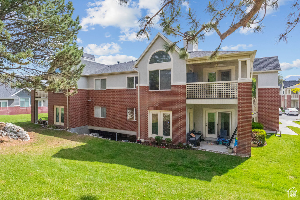 Rear view of property with a balcony, a yard, stucco siding, and a patio area