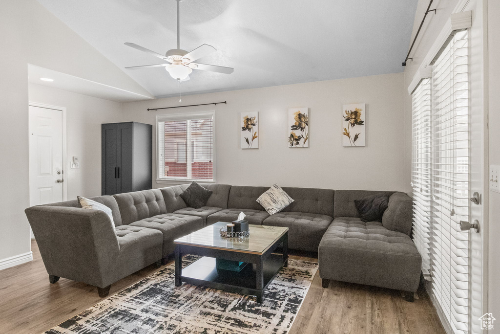 Living area with wood finished floors, vaulted ceiling, a ceiling fan, and baseboards
