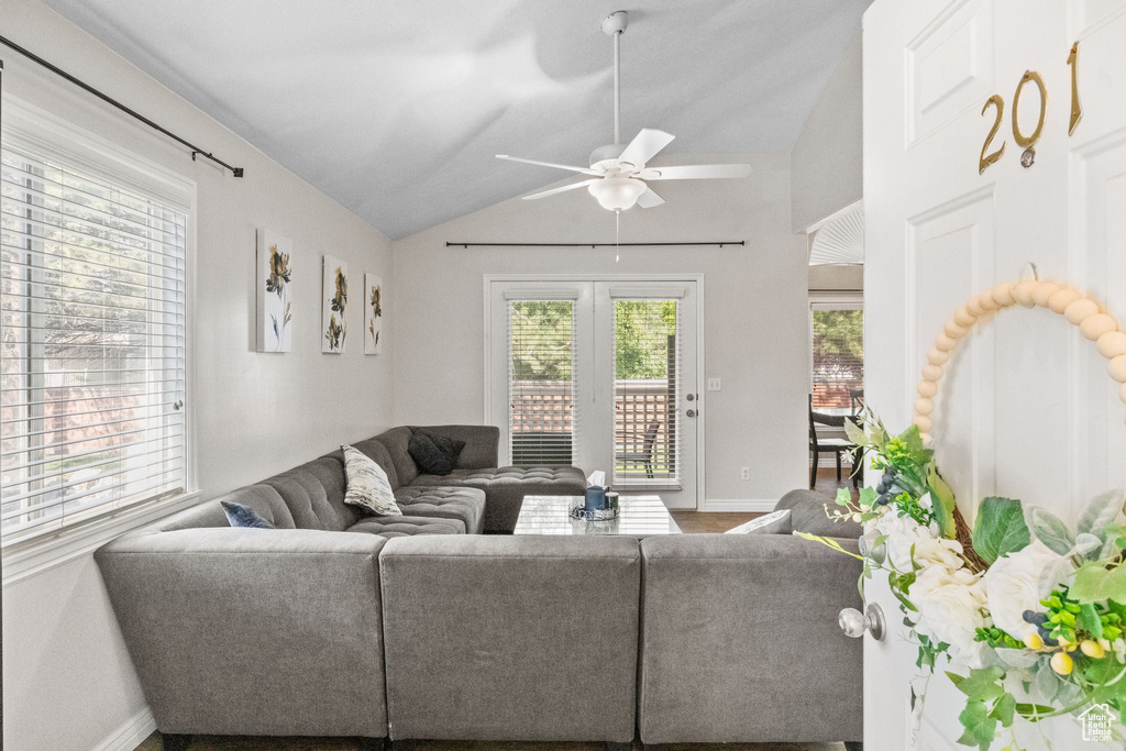 Living room with vaulted ceiling, baseboards, and a ceiling fan