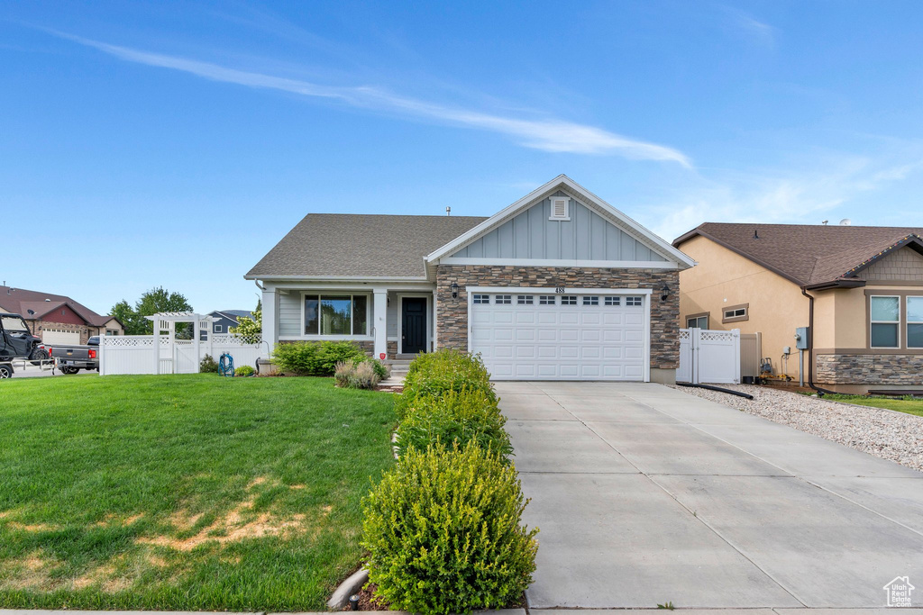 View of front of house featuring stone siding, an attached garage, concrete driveway, and board and batten siding