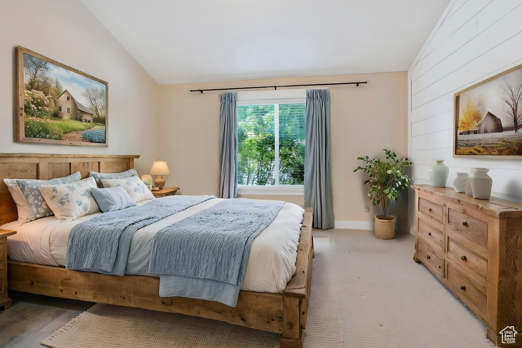Bedroom featuring vaulted ceiling and wooden walls