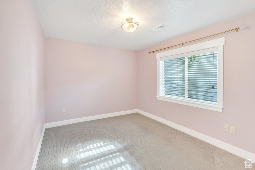 Carpeted empty room featuring baseboards and a textured ceiling
