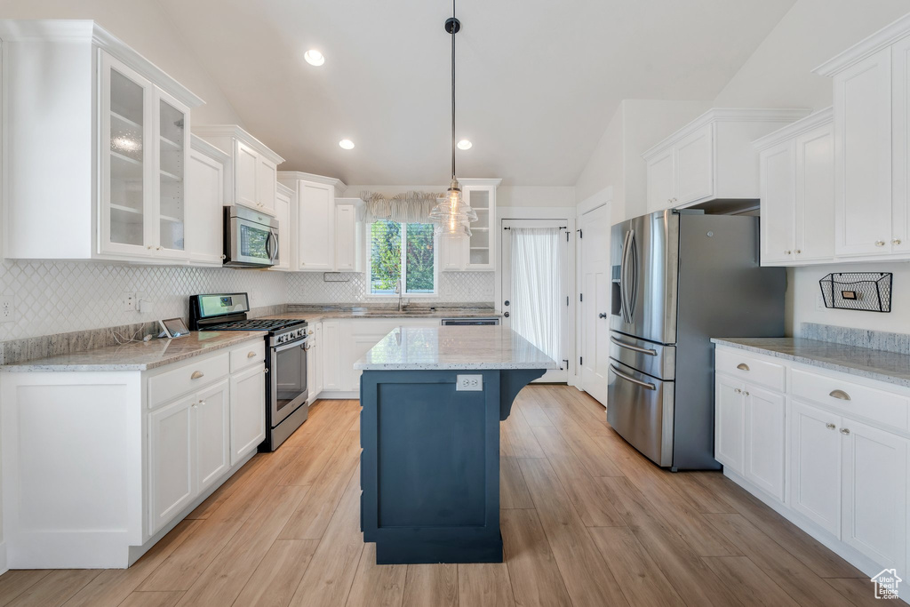 Kitchen featuring stainless steel appliances, a sink, white cabinetry, backsplash, and vaulted ceiling